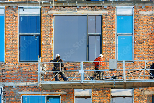 Obraz na płótnie Builders are installing large panoramic windows in a modern residential building using a winch and a mobile platform. w salonie