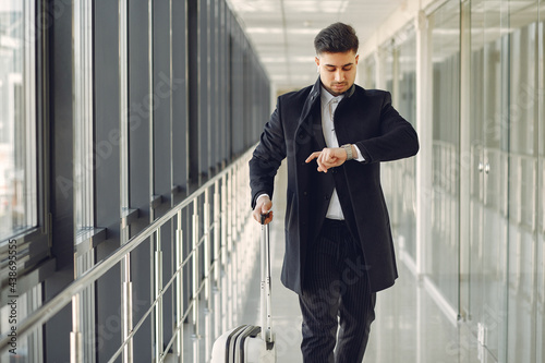 Elegant man at the airport with a suitcase