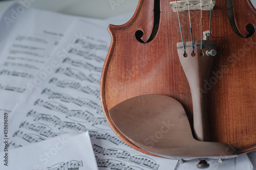 Close up detail on violin body, bow and music notes background. Classic instrument with copy space area 