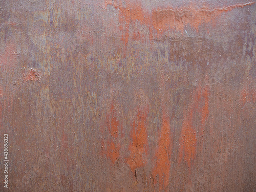Rusty texture of the garage wall. Metal sheet with peeling red paint and cracks.
