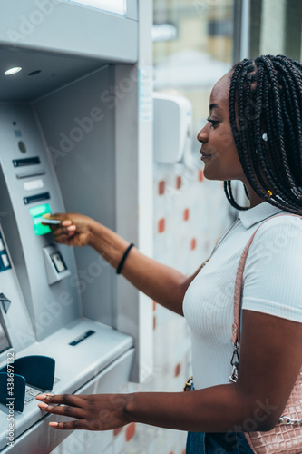 African american woman using credit card and withdrawing cash at the ATM