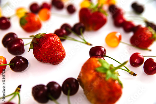 Fototapeta Naklejka Na Ścianę i Meble -  Red and yellow ripe cherries and strawberries. Berries are randomly scattered on a white background.