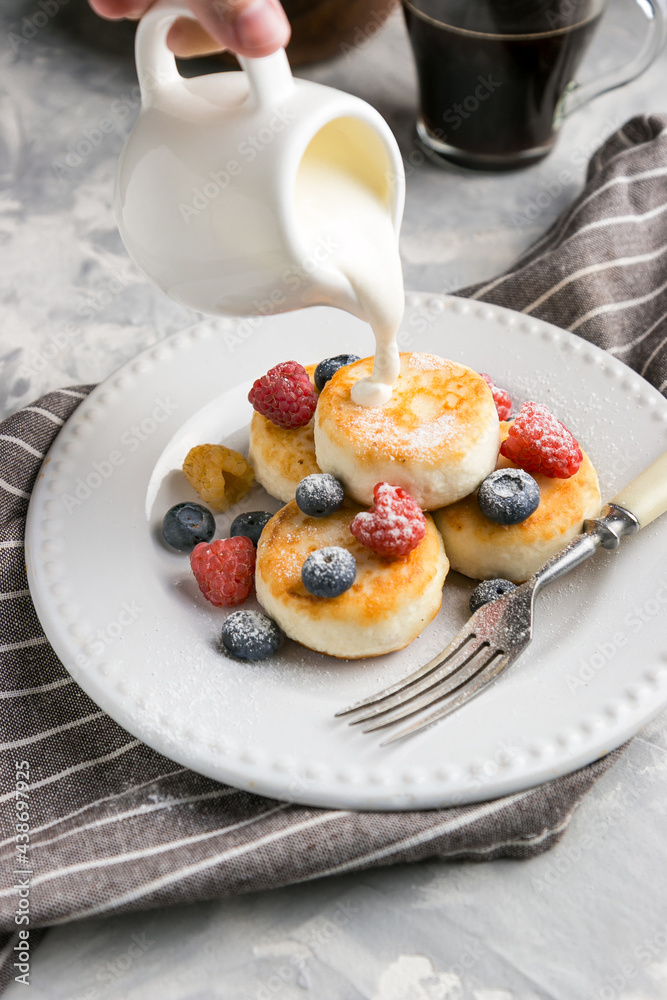 Sour cream is poured onto cheesecakes with berries Sour cream is poured onto cheesecakes with berries