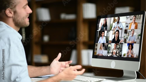 Group brainstorm, online business briefing. Successful caucasian man uses computer for a video call, virtual meeting with partners, sits at workplace, diverse multiracial people on the computer screen