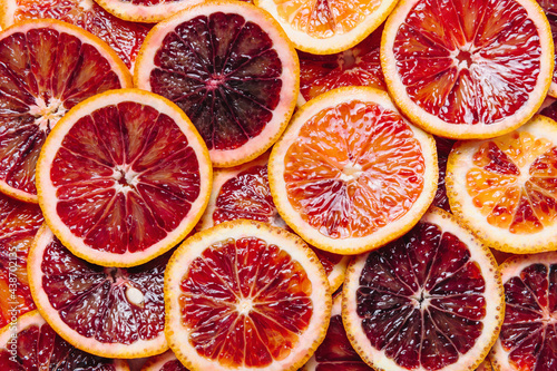 Bright colorful background of fresh ripe sliced blood oranges. Close up pattern, flat lay, top view.
