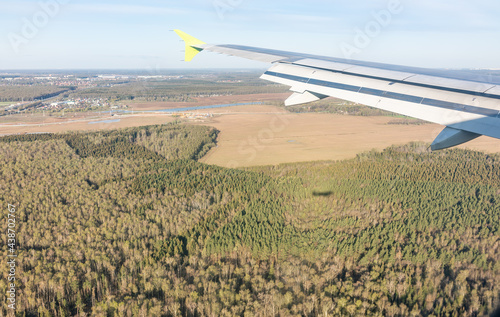 View of airplane wing, blue skies and the land during landing in Moscow, Russia. Airplane window view.