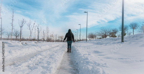 woman with her back turned walking across a snow-covered street