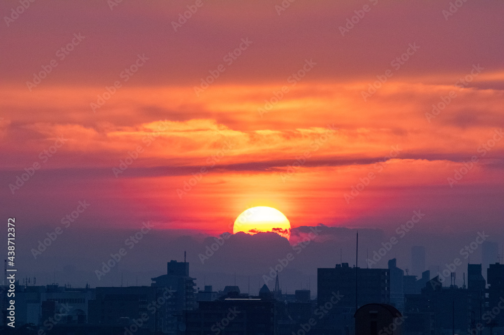 Fototapeta premium 神戸市東灘区の高層マンションからの日の出、東の空がオレンジ色に染まり、神戸・芦屋・西宮の街並みがシルエットで浮かぶ。一日の始まり。