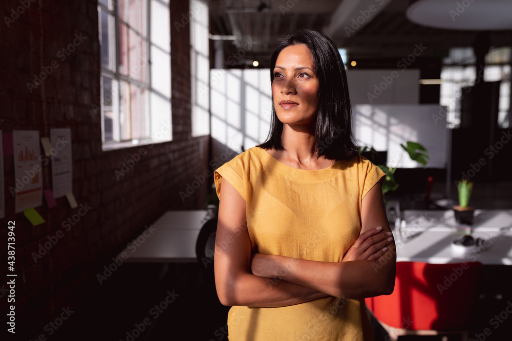 Portrait of caucasian businesswoman standing in sunny office looking away, with shadow on face