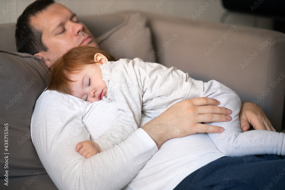 Toddler and dad sleeping on the couch during the day, concept children's day and Parental care. Focus on the hands. Toddler and dad sleeping on the couch during the day, concept children's day and Parental care. Focus on the hands.