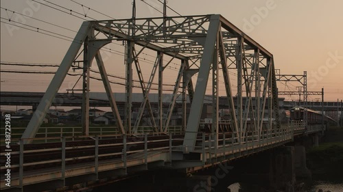 Hankyu train crossing a bridge at sunset near Osaka. photo