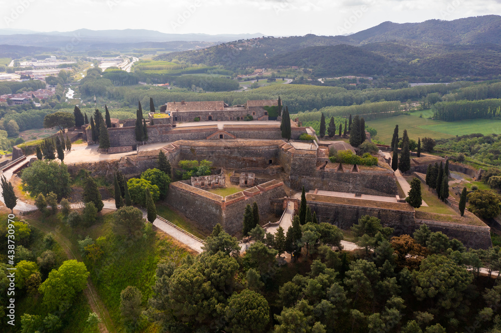 Panoramic aerial view of medieval walled fortress on top of basalt hill in Hostalric village in spring, Catalonia, Spain.