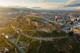 Aerial view of ancient fortified citadel Gori Fortress on rocky hill on background of cityscape at sunrise in spring, Georgia.