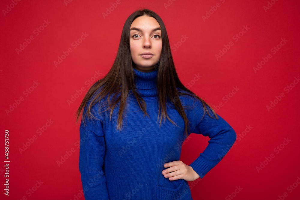 Fototapeta premium Young calm serious beautiful brunette woman with sincere emotions isolated on background wall with copy space wearing casual trendy blue sweater