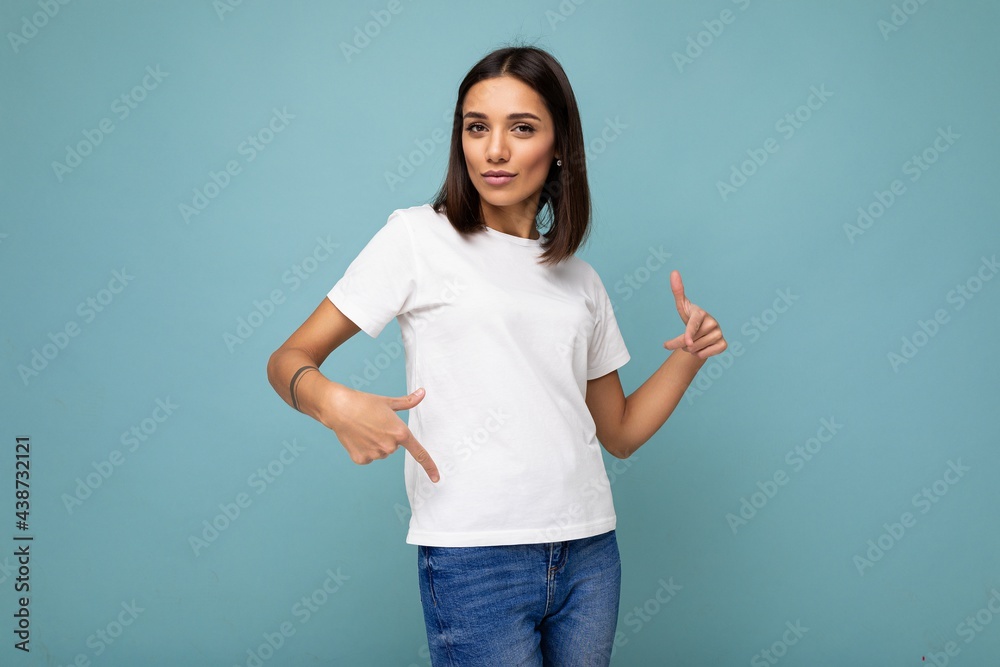Attractive self-confident young brunette woman in casual white t-shirt for mockup isolated on blue background with free space Attractive self-confident young brunette woman in casual white t-shirt for mockup isolated on blue background with free space