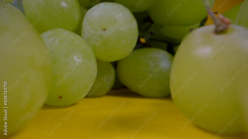 Macro dolly shot of ripe green grapes presenting on yellow surface. Macro dolly shot of ripe green grapes presenting on yellow surface.