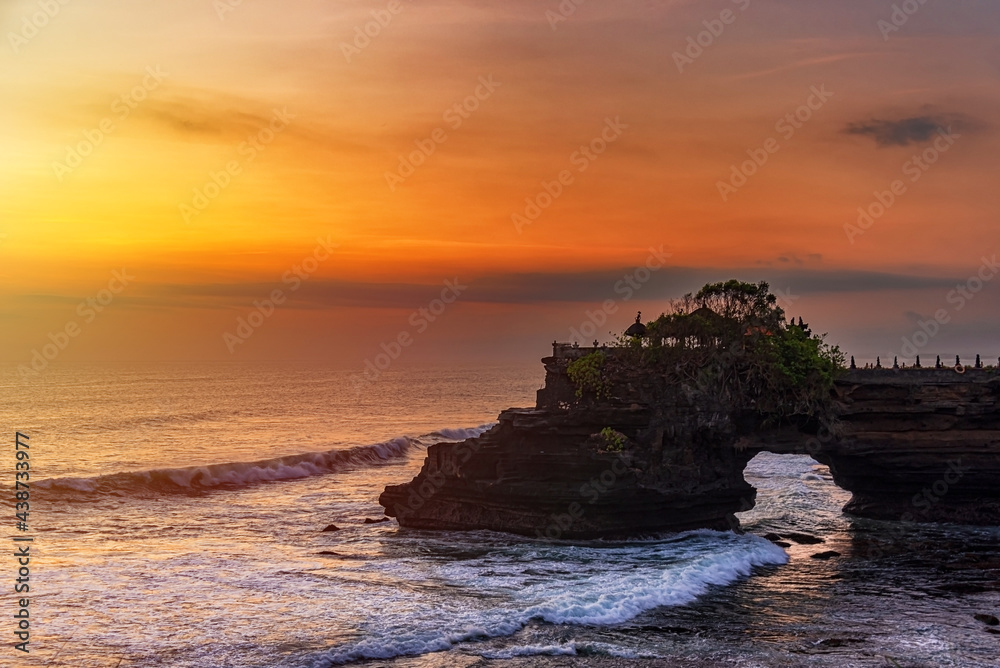 Silhouette of Pura Batu Bolong in golden sunset it the traditional Balinese temple located on a rocky, in the Tanah Lot area, Bali, Indonesia.