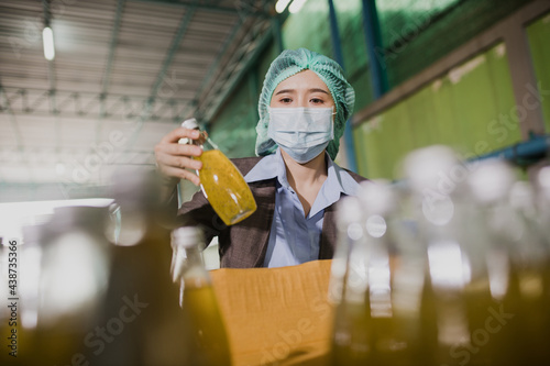 Young female manager factory checking juice bottles before shipment. Inspection quality control. Manager inspecting production line at drinks production factory