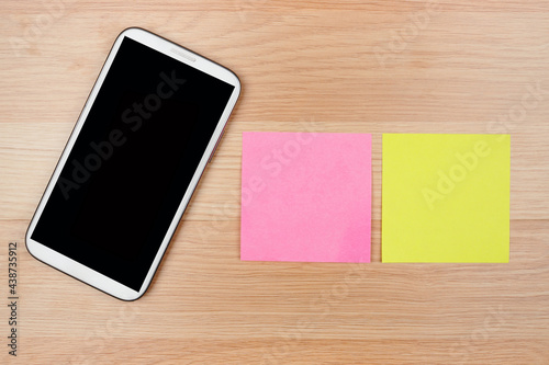 Smart phone on wooden plate with empty blank note on wooden background, business concept