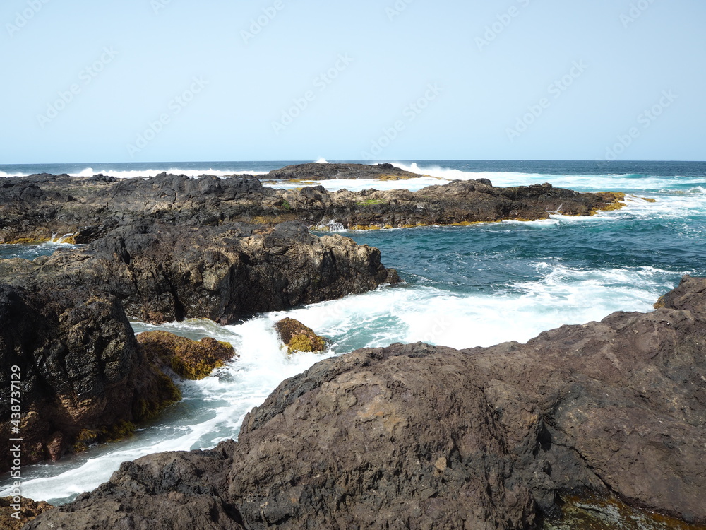 Volcanic coast of the Atlantic Ocean. Waves crash against black rocks. Tenerife, Canary Islands 