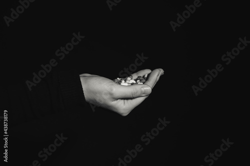 Hand with pills on dark bac...