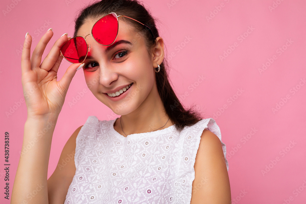 Closeup photo shot of beautiful positive young brunette woman wearing summer casual clothes and stylish sunglasses isolated over colorful background wall looking at camera Closeup photo shot of beautiful positive young brunette woman wearing summer casual clothes and stylish sunglasses isolated over colorful background wall looking at camera