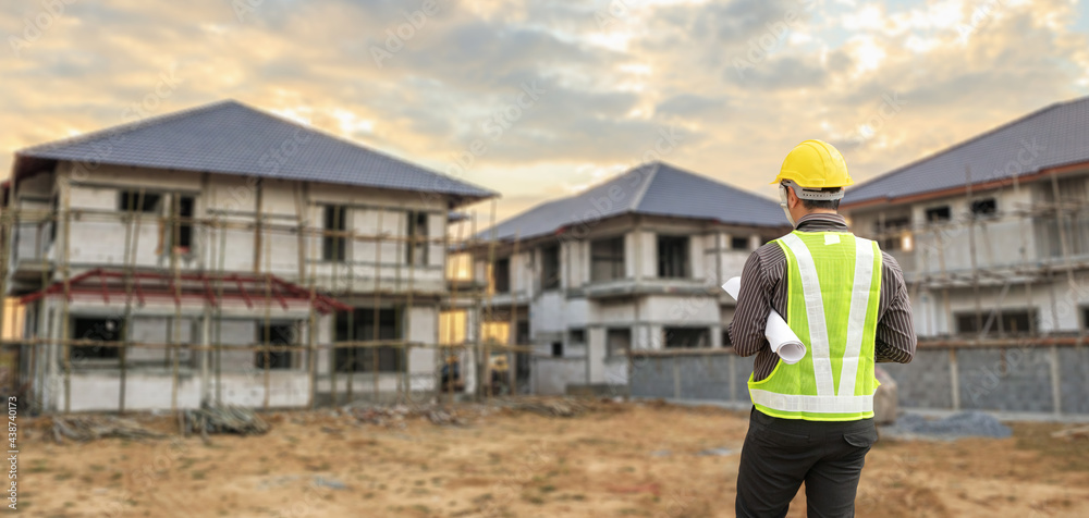 young professional engineer in protective helmet and blueprints paper at the house building construction site young professional engineer in protective helmet and blueprints paper at the house building construction site
