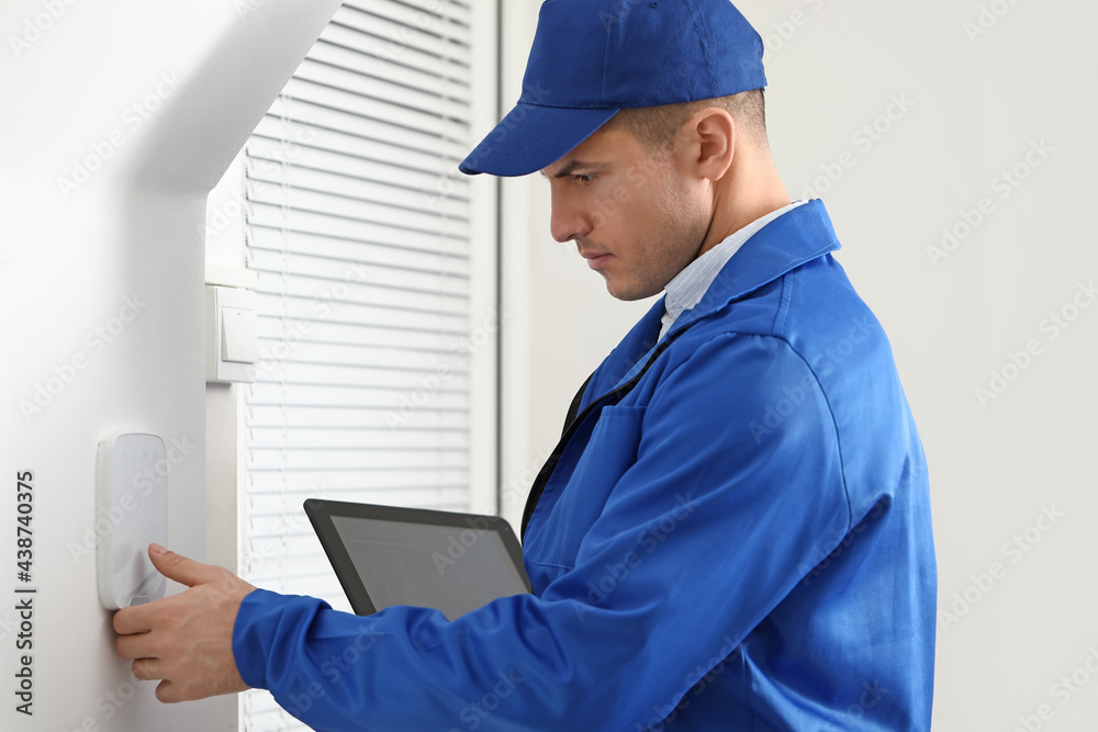 Worker with tablet computer checking alarm system indoors Worker with tablet computer checking alarm system indoors
