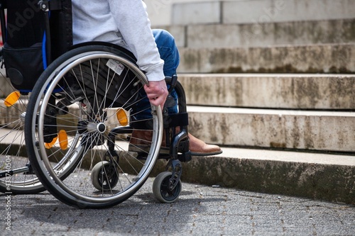 man in wheelchair looking at stairs