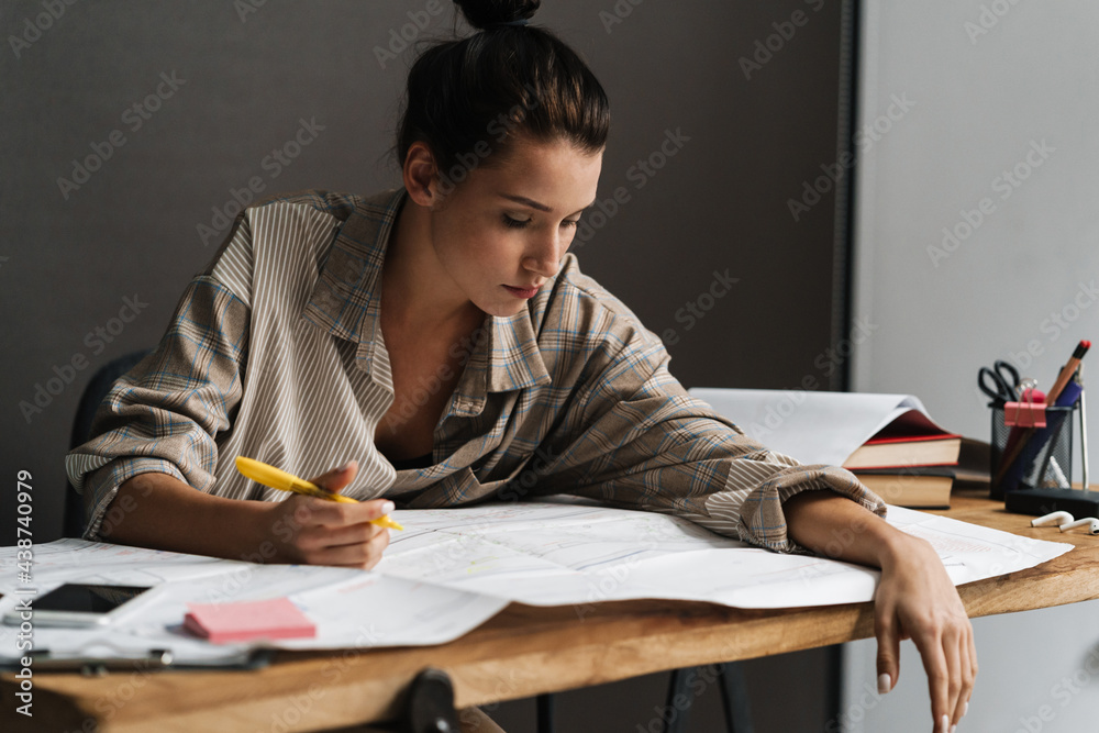 Young brunette woman drinking coffee Young brunette woman working with drawings while sitting at desk working with drawings Young brunette woman drinking coffee Young brunette woman working with drawings while sitting at desk working with drawings