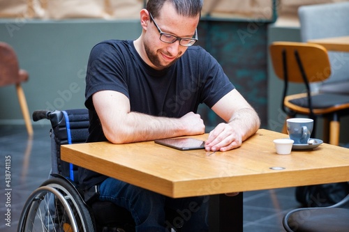 man in wheelchair looking at ipad tablet in restaurant