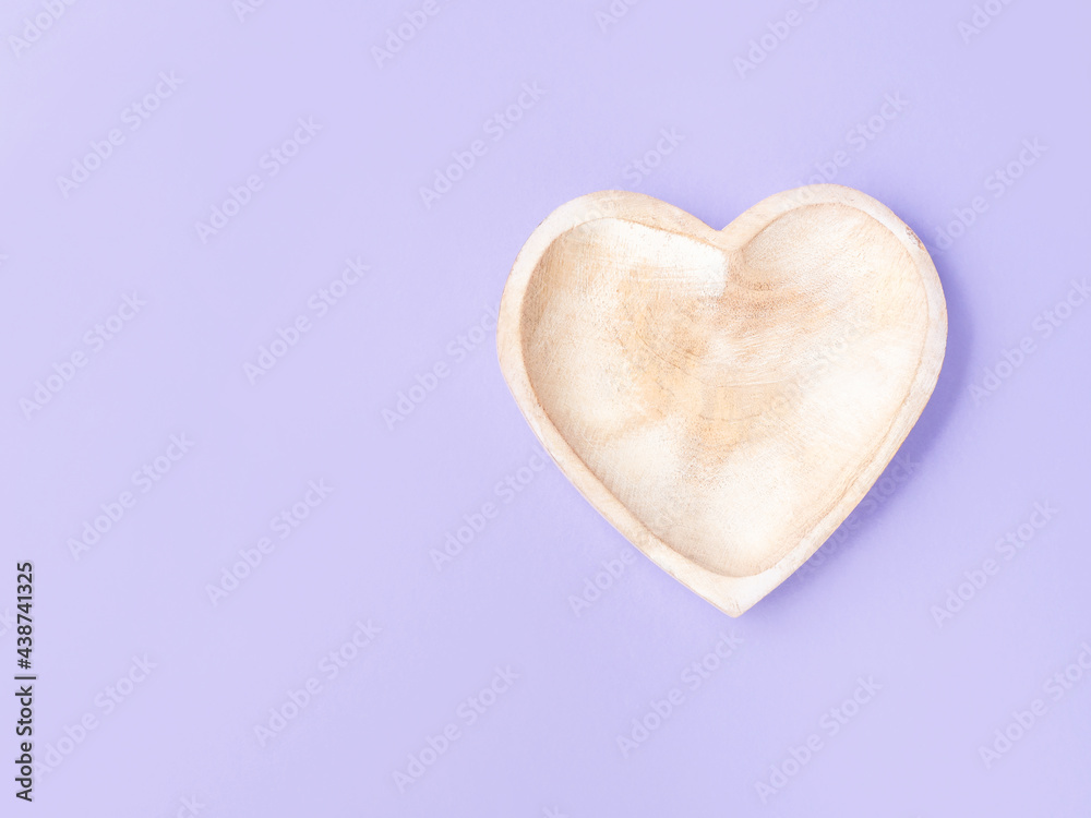 Empty heart shaped wooden dish on purple background