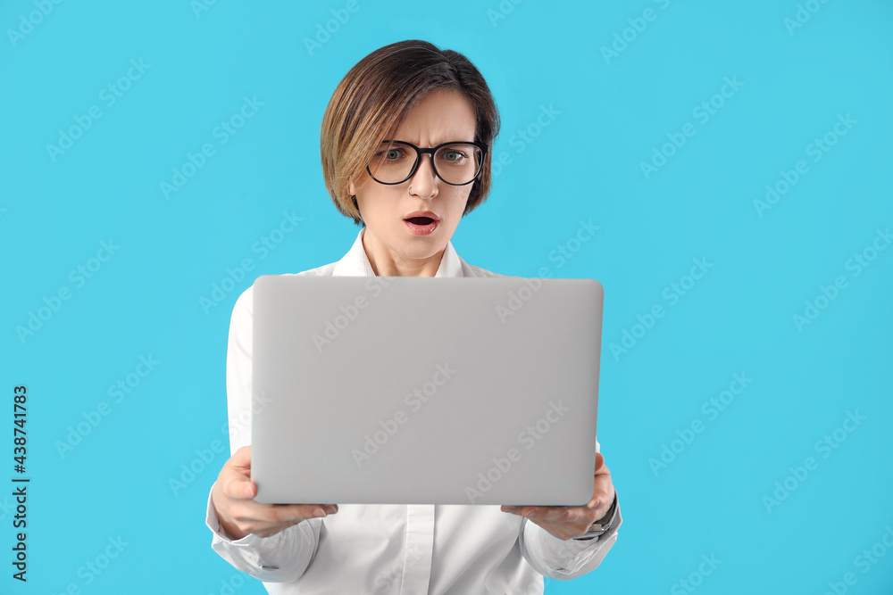 Shocked female programmer with laptop on color background Shocked female programmer with laptop on color background