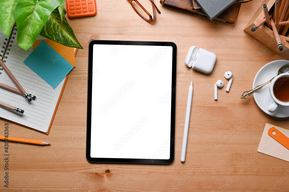 Top view mock up digital tablet, stylus pen, earphone, notebook and stationery on wooden table. Top view mock up digital tablet, stylus pen, earphone, notebook and stationery on wooden table.