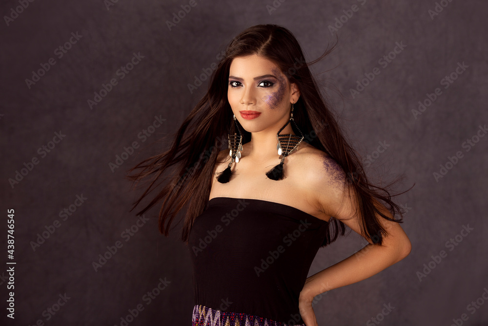 Fashion photo of a beautiful model with long hair, wearing black tube top, long dangling earrings, fashion pose, hands on hips, studio portrait, dark background.