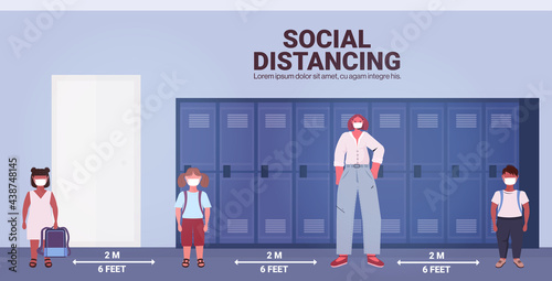 teacher and pupils in protective masks keeping distance to prevent coronavirus pandemic social distancing