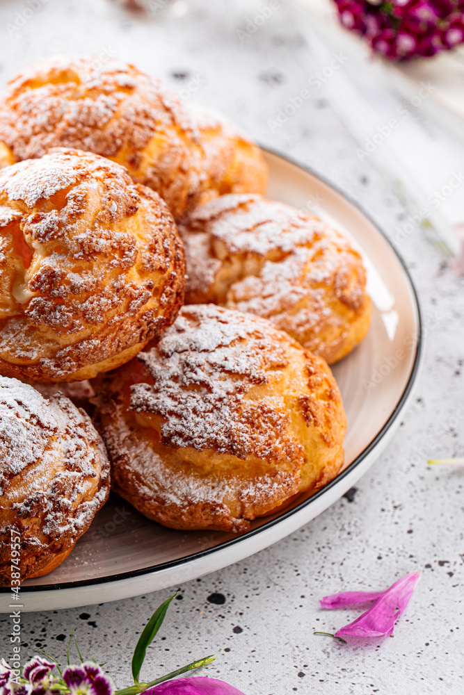 Fresh baked choux pastry cakes with powdered sugar Fresh baked choux pastry cakes with powdered sugar