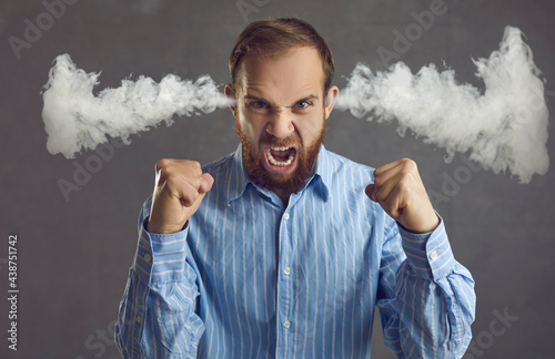 Angry crazy tired bad tempered young office manager or business man feeling pissed off loses control and yells in tantrum venting negative emotions steam coming out of ears isolated on grey background photo
