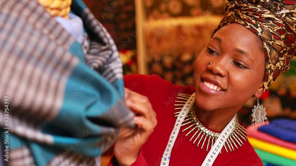 tanzanian woman with snake print turban over hear working in fabrics shop