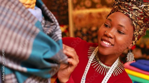 tanzanian woman with snake print turban over hear working in fabrics shop