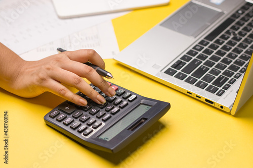 Closeup of using calculator on yellow background stock image.
