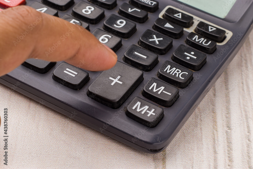 Closeup of using calculator on white textured background stock image.