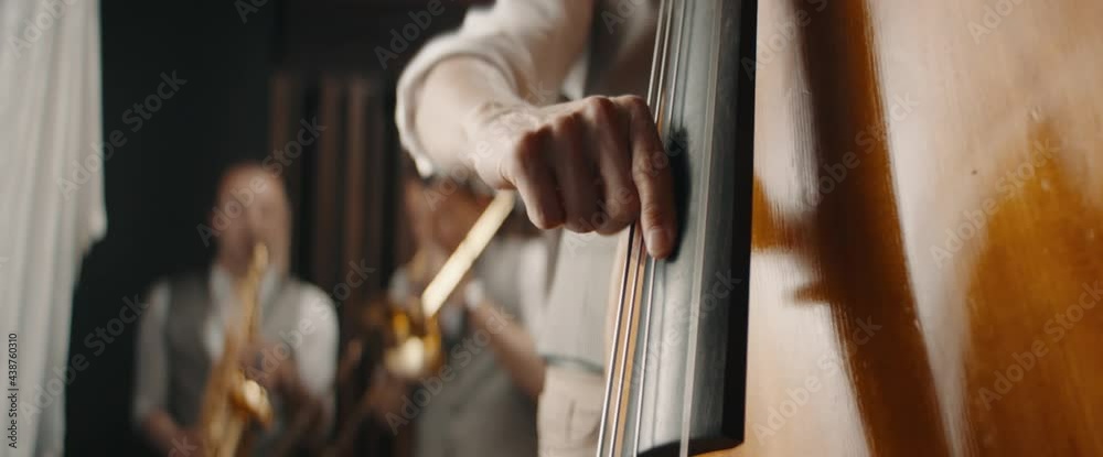 CU Caucasian male playing double bass during jazz band rehearsal or concert. Shot with 2x anamorphic lens CU Caucasian male playing double bass during jazz band rehearsal or concert. Shot with 2x anamorphic lens