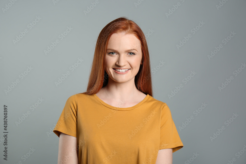 Candid portrait of happy young woman with charming smile and gorgeous red hair on grey background Candid portrait of happy young woman with charming smile and gorgeous red hair on grey background