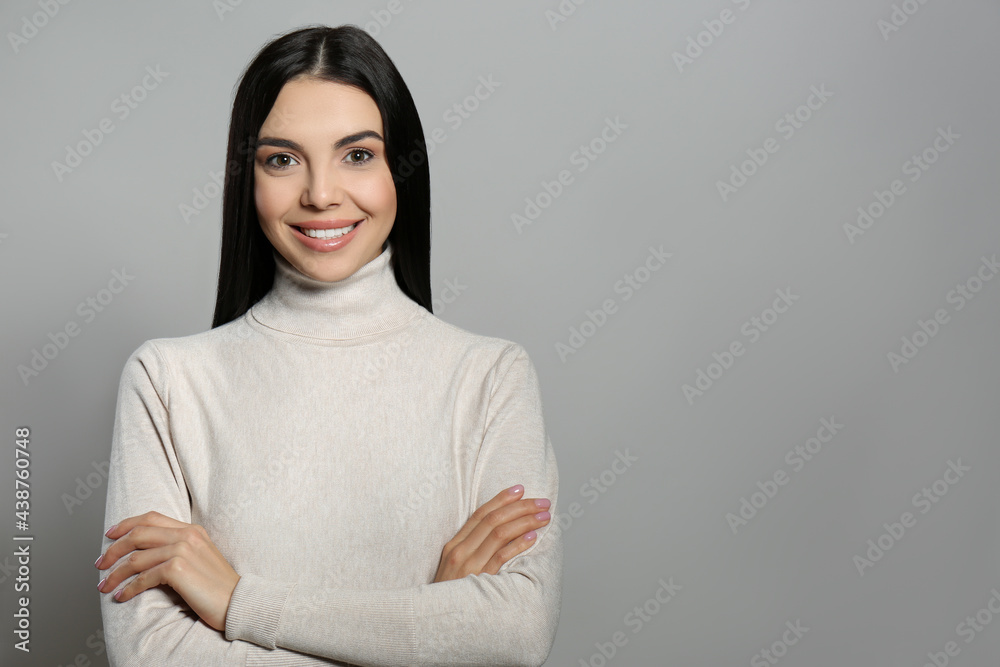 Portrait of happy young woman with beautiful black hair and charming smile on light grey background, space for text Portrait of happy young woman with beautiful black hair and charming smile on light grey background, space for text