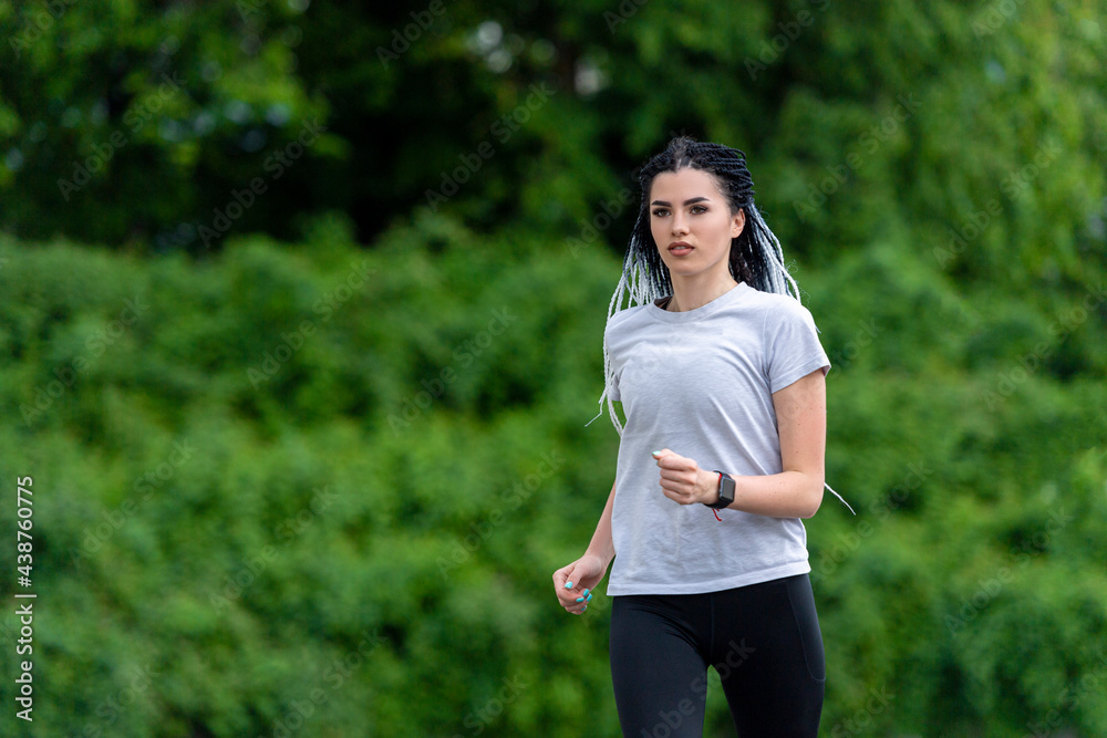 Woman with african braids running in city park. Sport activities on street and music Woman with african braids running in city park. Sport activities on street and music