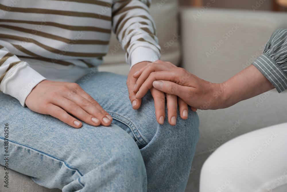 Psychotherapist holding patient's hand indoors, closeup view