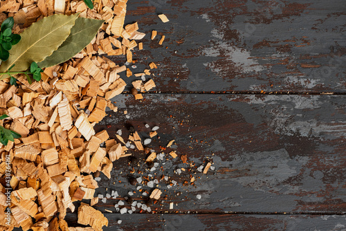 Frame from wood chips for smoking on a dark wood background top view. Copy space for text. Wood chips for smoking fish or meat, flat lay.
