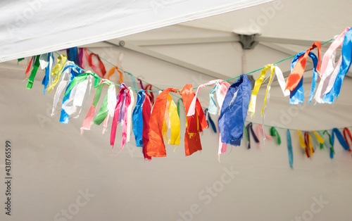 colorful ribbons tied to a rope, in a white tent, outside. Trade, holidays, decoration, colored ribbons, City Day. © Olga