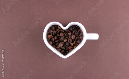 Roasted coffee beans in heart shaped mug on brown background © Valeria F
